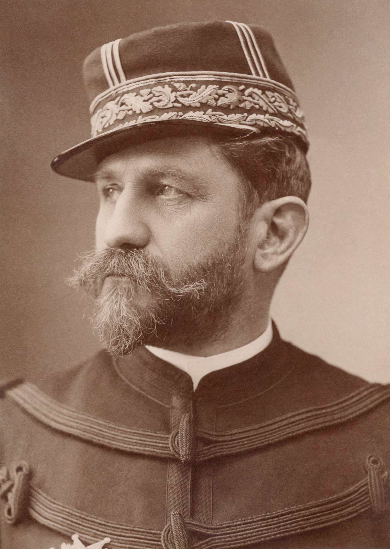 Portrait en gros plan d’un homme barbu portant un chapeau orné et un col rayé, style ancien.