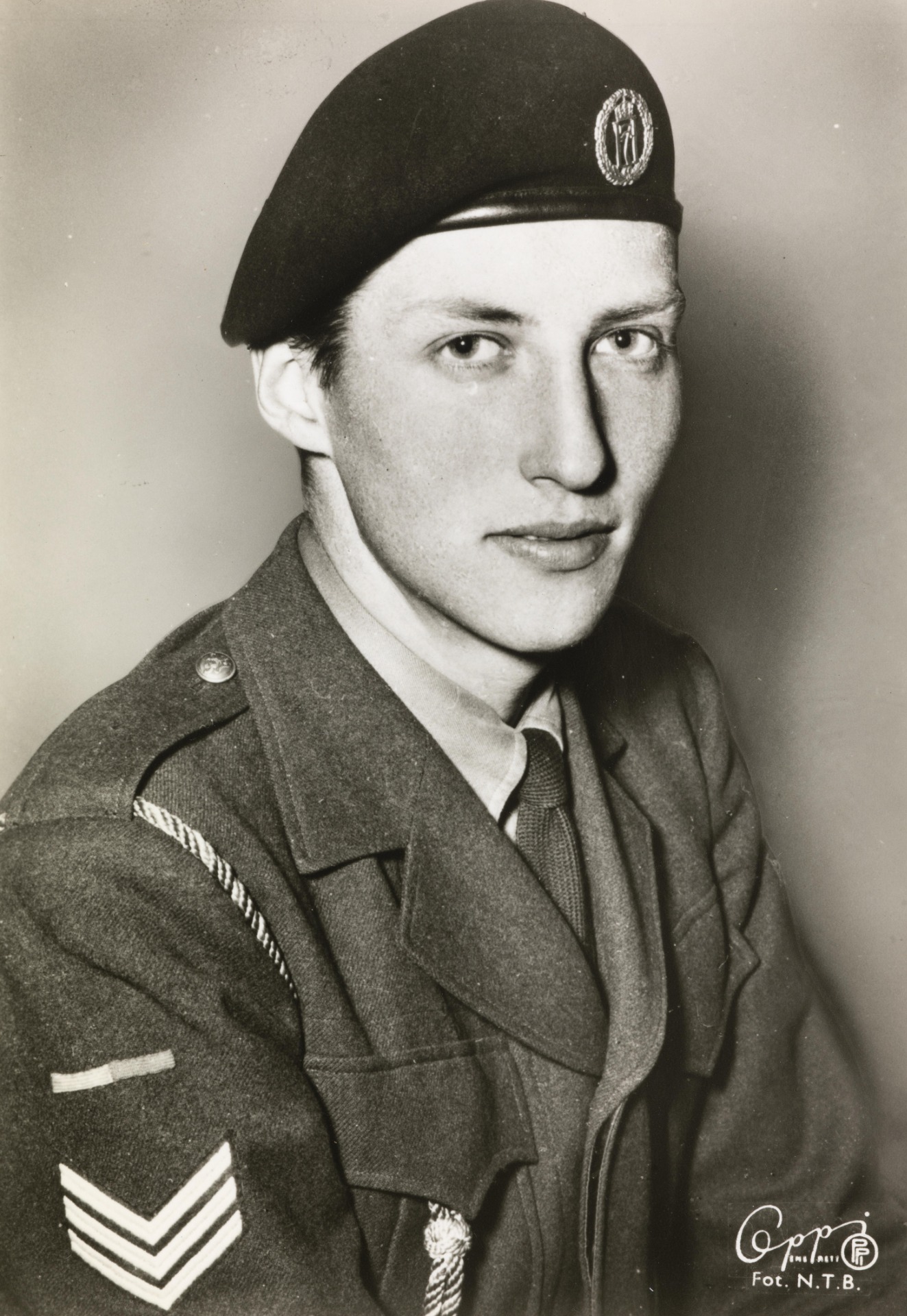 Portrait noir et blanc d’un homme en uniforme, portant un béret, regardant l’objectif.